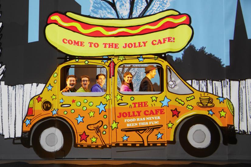 a group of people are in a food van with a hotdog on the top
