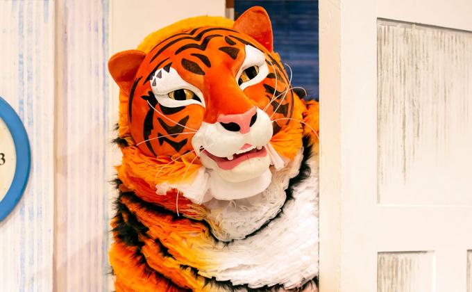 A clock states it is 4pm, a tiger peers through a door