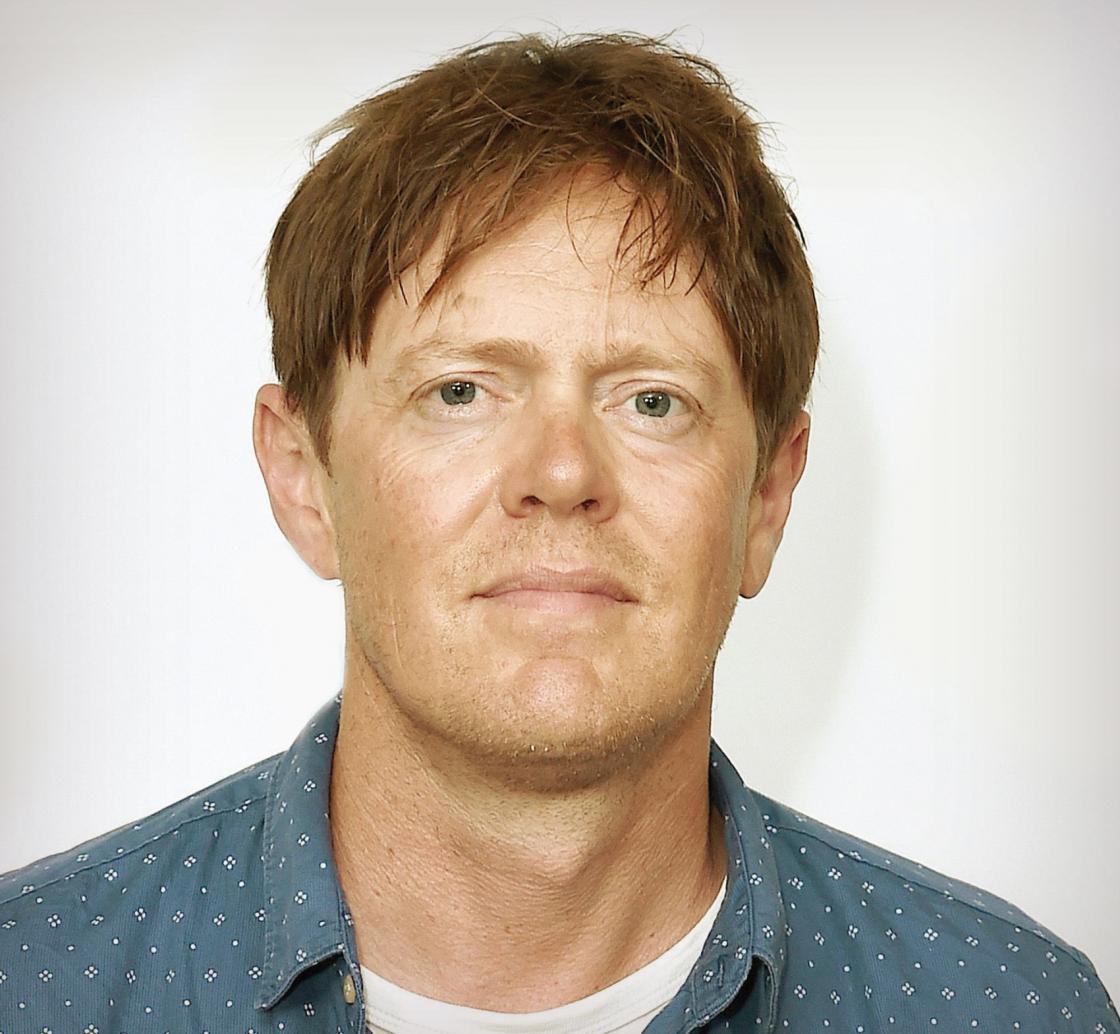 A man with short strawberry blonde hair in a blue shirt