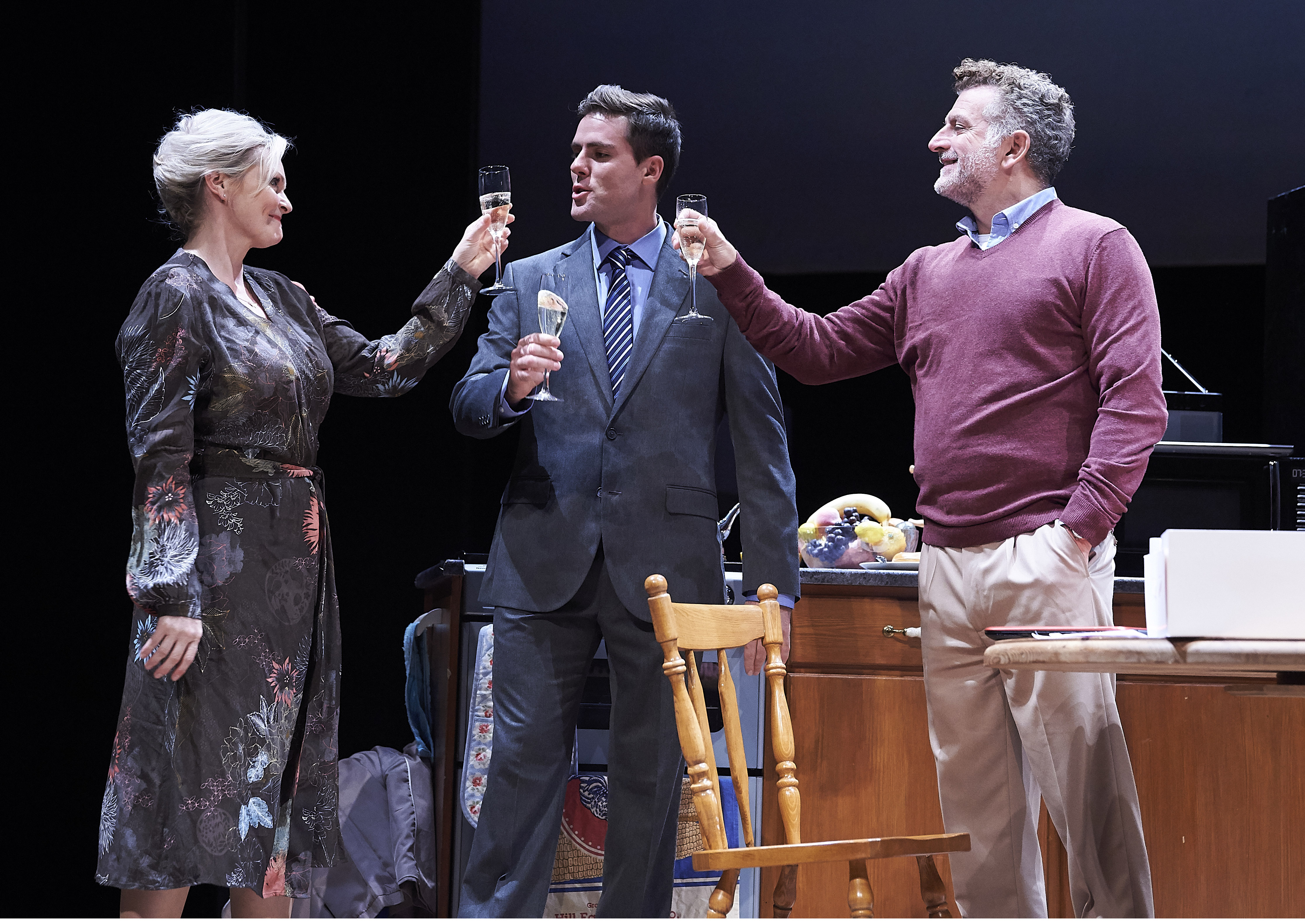 A woman and two men make a toast with champagne