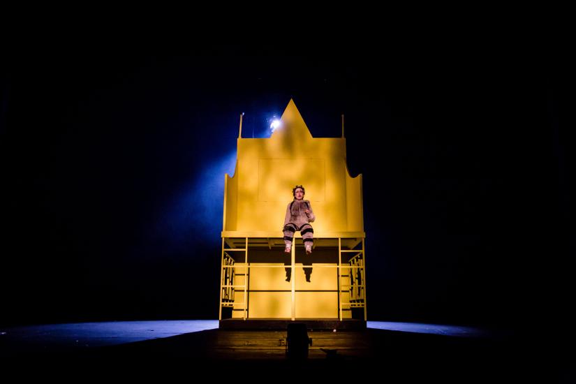 A young prince sits on a giant yellow throne.