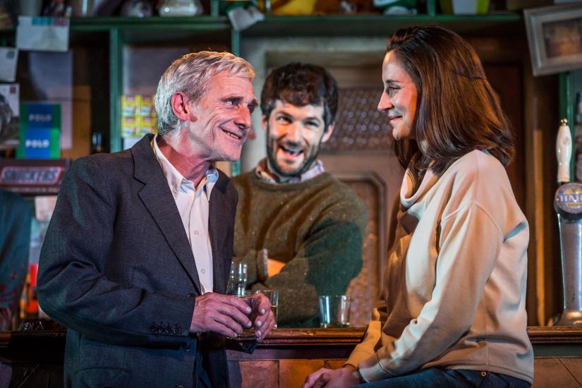 A woman and a man smiling at each other in a pub