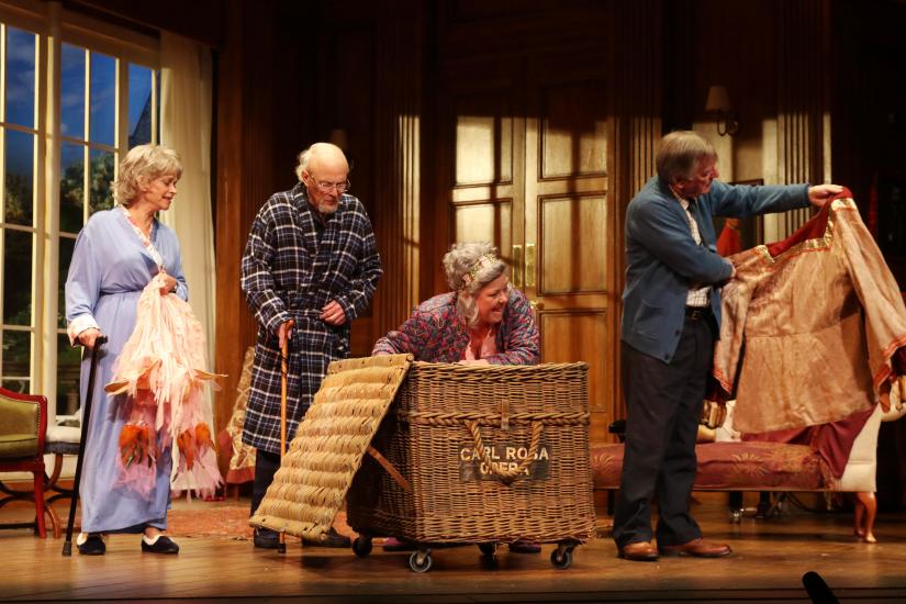 Two men and two women pulling costumes out of a wicker box
