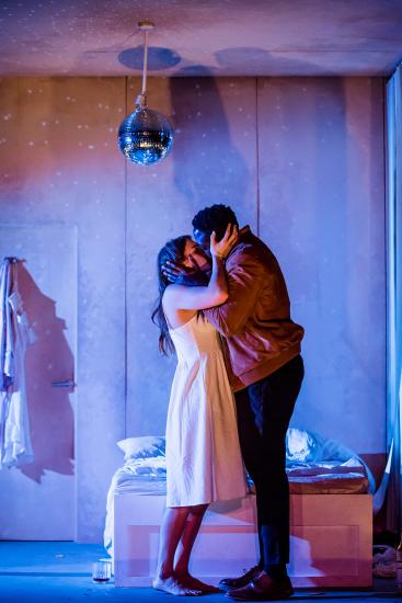 A man and woman kissing underneath a disco ball