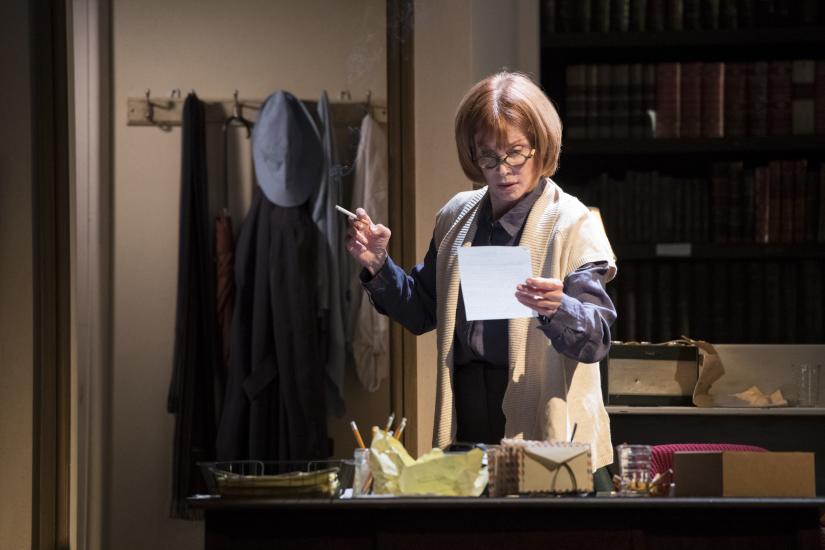 A woman stood smoking and reading a letter