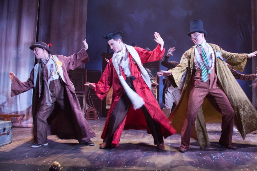 Three men dancing in hats and long coats
