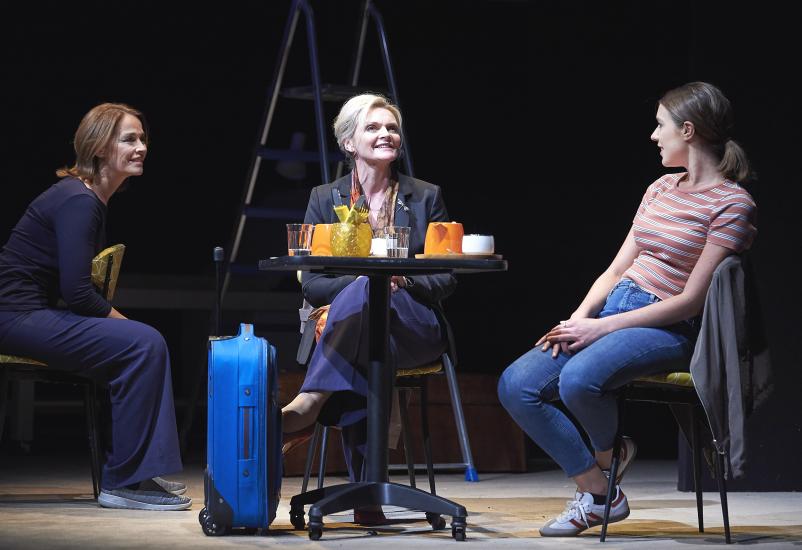 Three women sit talking at a table