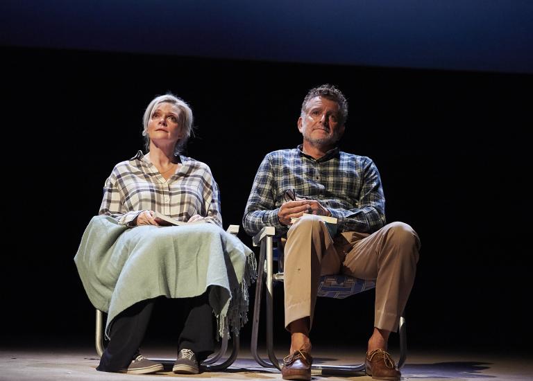 A man and woman sit on camping chairs