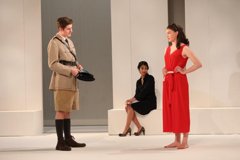 A woman in red looks in annoyance at a man in uniform - a woman watches from afar