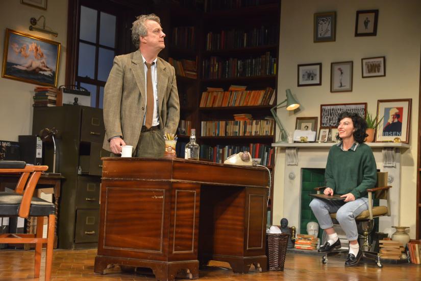 A man and a woman are having a conversation in an office the man stands behind a desk