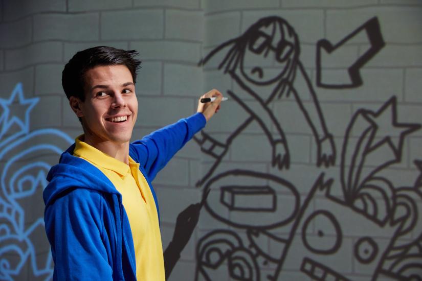 a boy points a whiteboard with cartoon on it