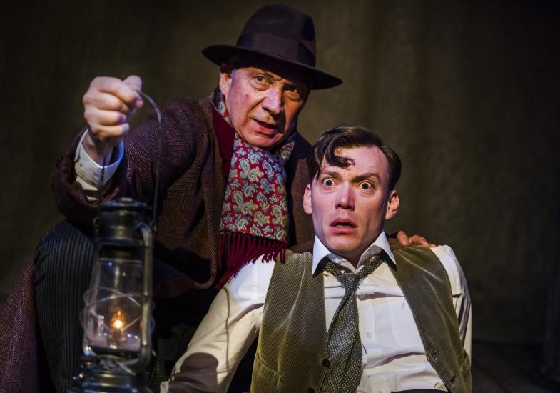 Two men look very scared, one is holding a gas lamp