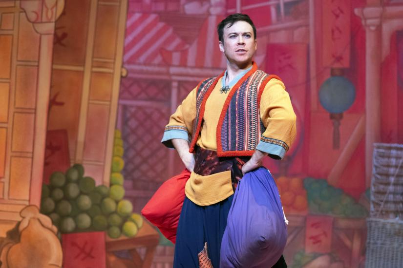 Aladdin looks heroic with his hands on his hips, he is carrying bags of laundry