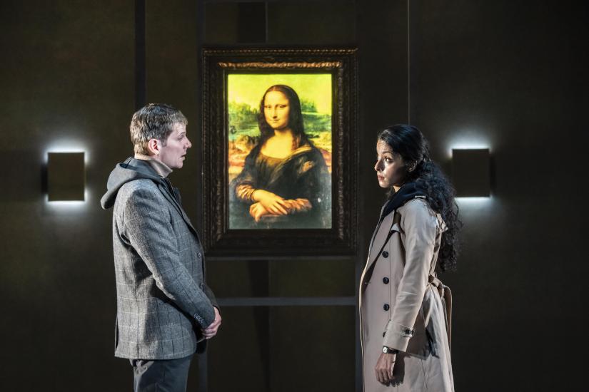A man and a woman stand in front of the Mona Lisa painting