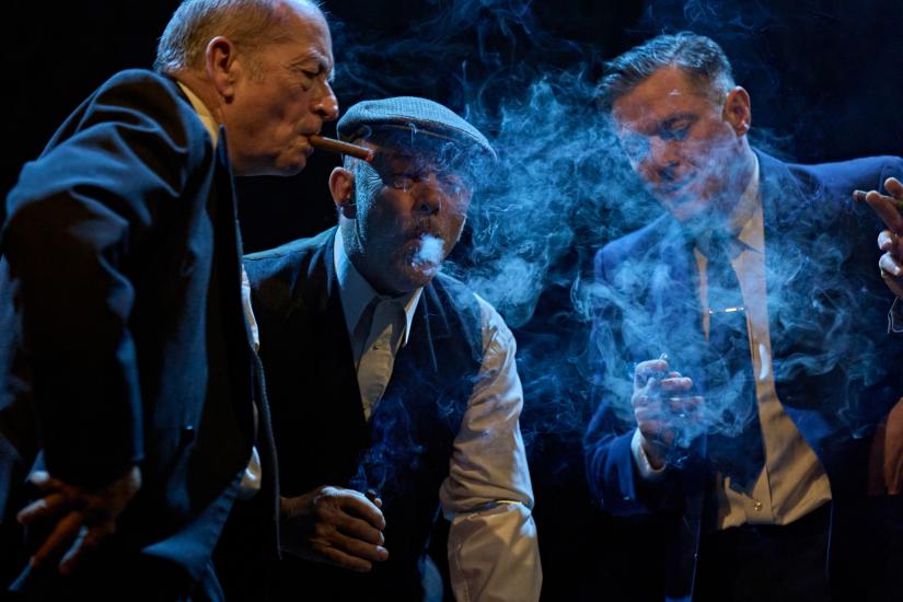 Three men smoke cigars together