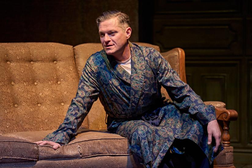 A man sits on a sofa in a patterned robe