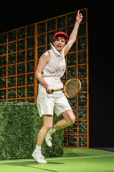 A tennis player holds her hand in the air in celebration