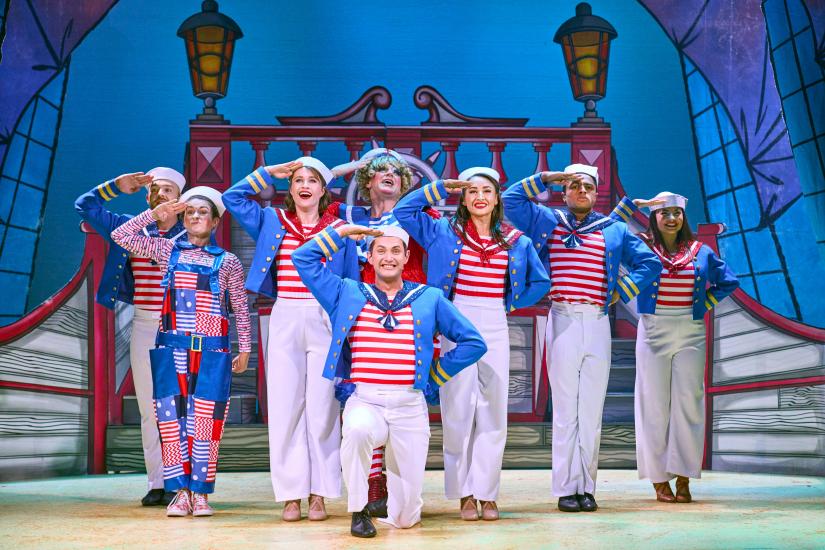 Sailors saluting, they are wearing red and white striped tops and blue jackets