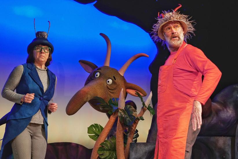 The blue and the orange alien look off stage, worried. A large beast stands behind them.