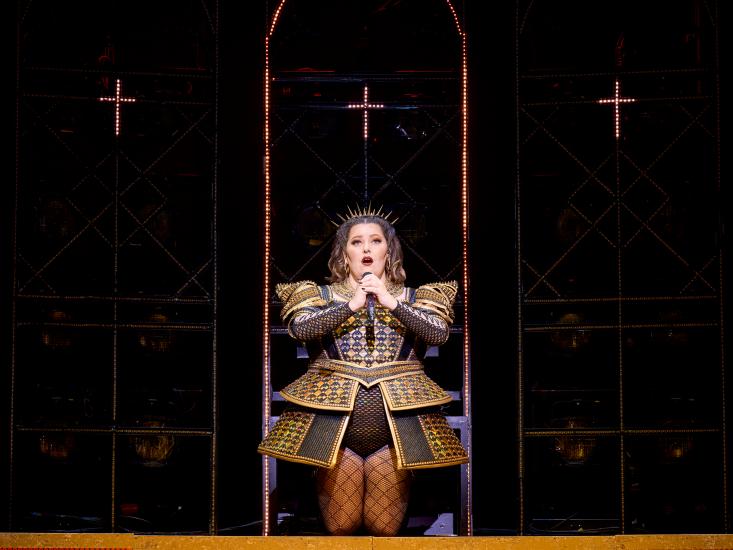 A queen sings into a microphone