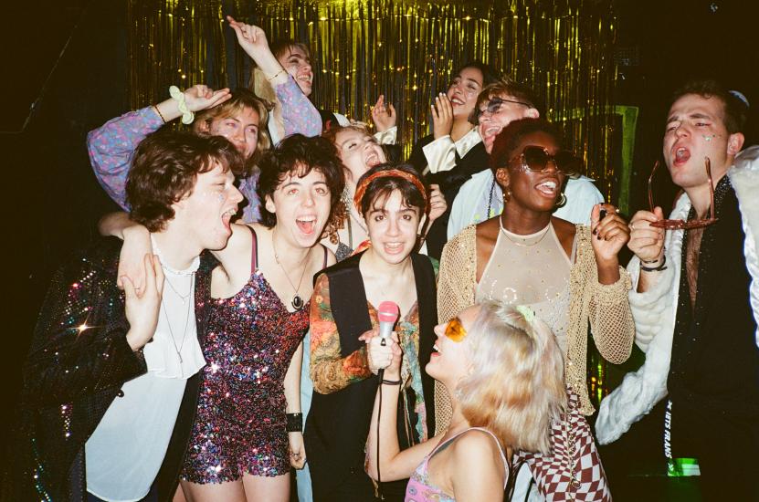 A group of young people in a nightclub singing karaoke 