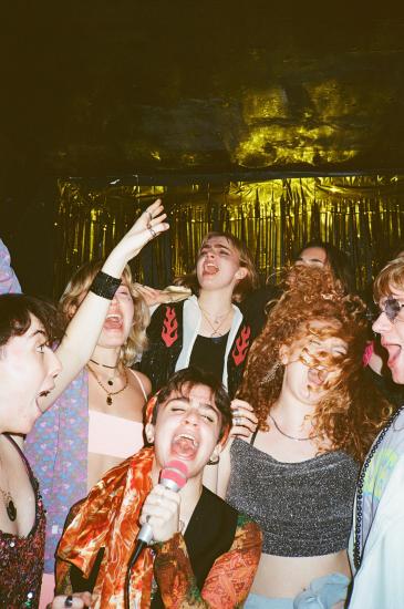 A group of young people in a nightclub singing karaoke 