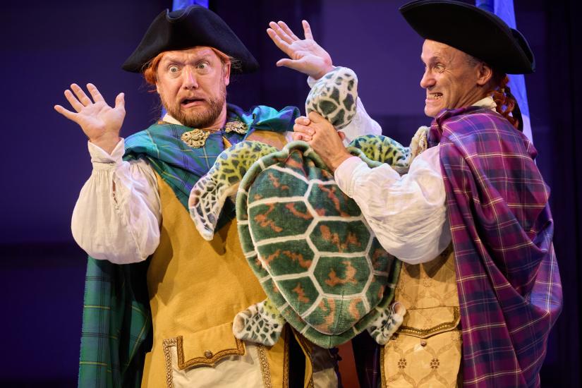 Two men with surprised faces, one holds a turtle