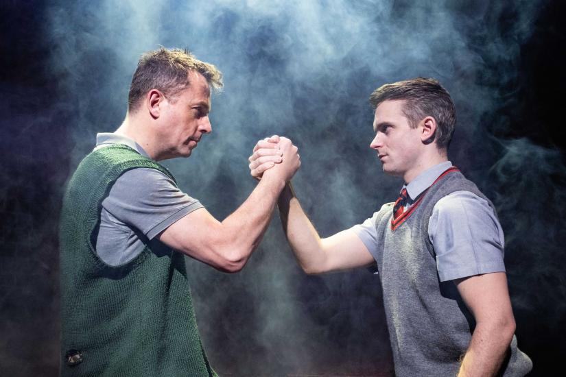 Two young boys grasping each other's hands, they are both wearing school uniform