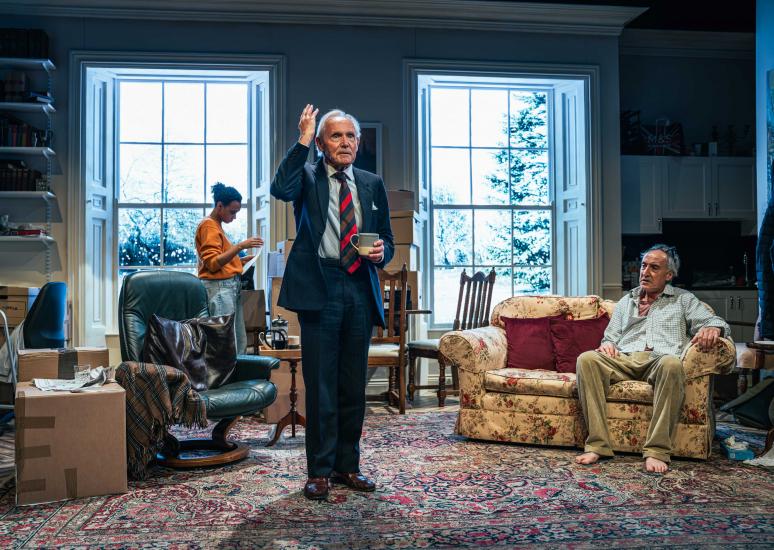 A group shot, a man stands holding a tea and has his arm raised by his head