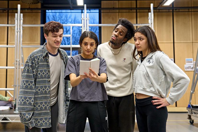 3 actors observe girl writing on notepad