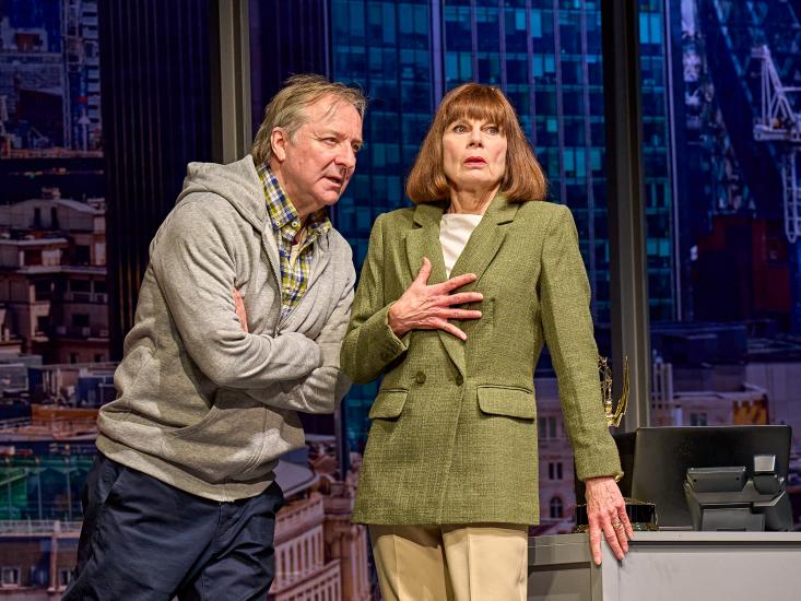 A man leans in to speak to a woman wearing a green suit