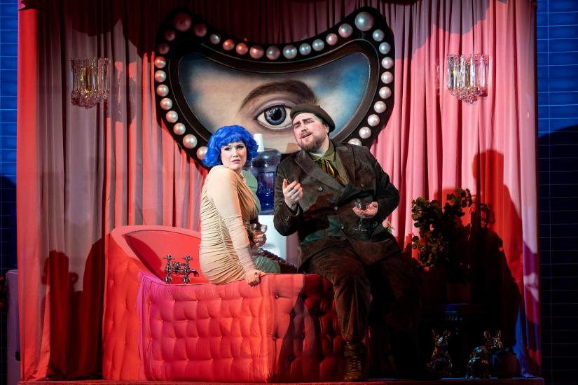 woman with blue hair and military man sit on a pink chair 