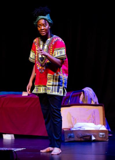 Nicholle Cherrie as Nina Simone on stage standing raising one arm in a passioned speech