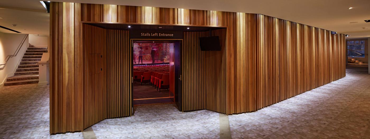 Auditorium foyer with wooden panels and lighting along the edges