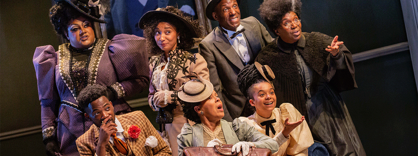 A group of actors in costume look towards the camera