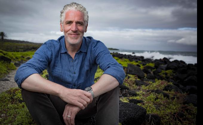 gordon buchanan sits on a rock in a field