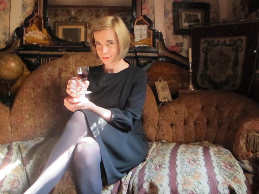 Lucy Worsley sitting on a chaise lounge with a glass of wine.