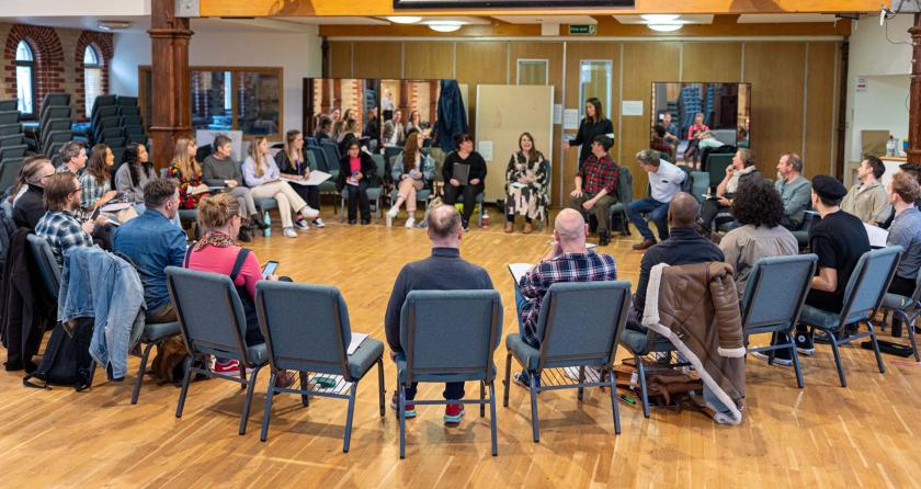 Cast members sitting in a circle reading scripts