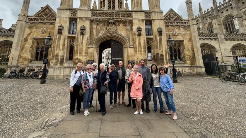 A group of volunteers smiling and waving in front of Kings College in Cambridge