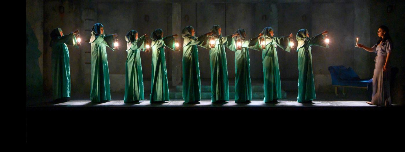 Characters in green costume in a line with candles