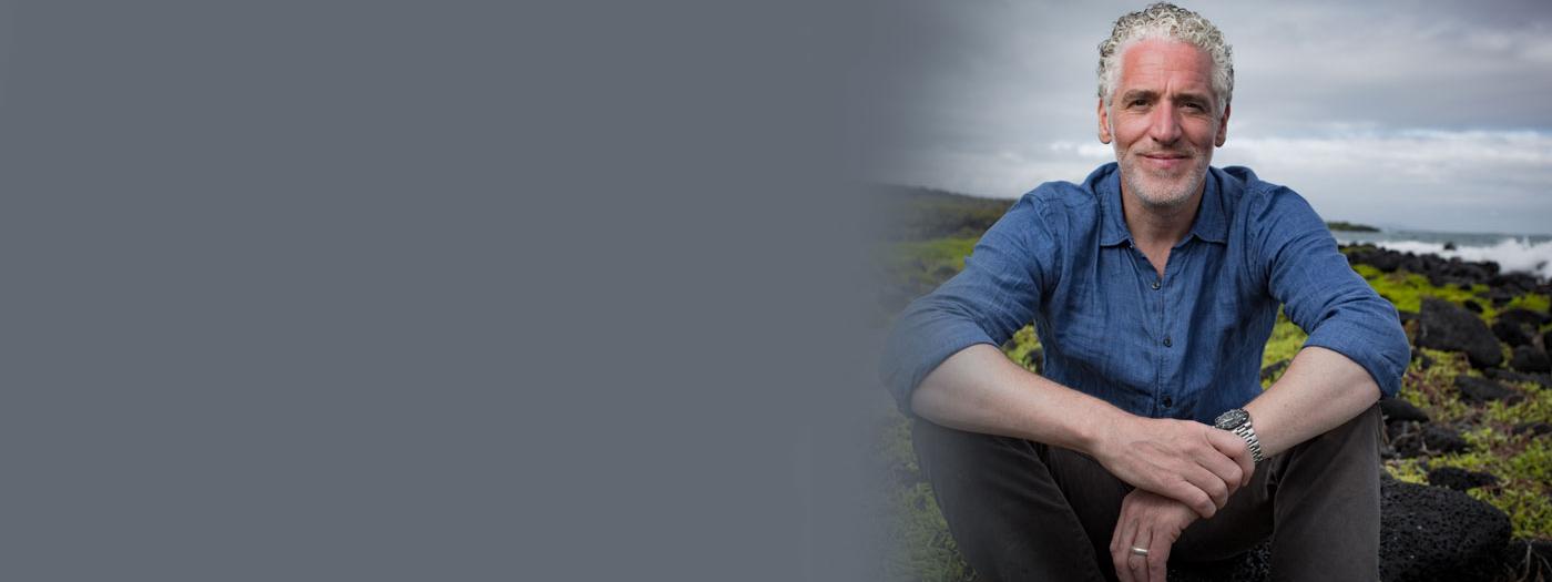 gordon buchanan sits on a rock in a field