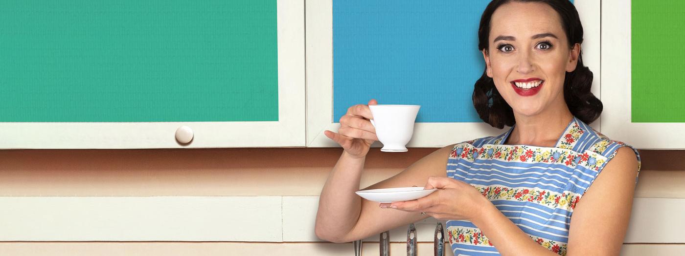 A 1950s housewife in an apron holding a cup of tea and a saucer