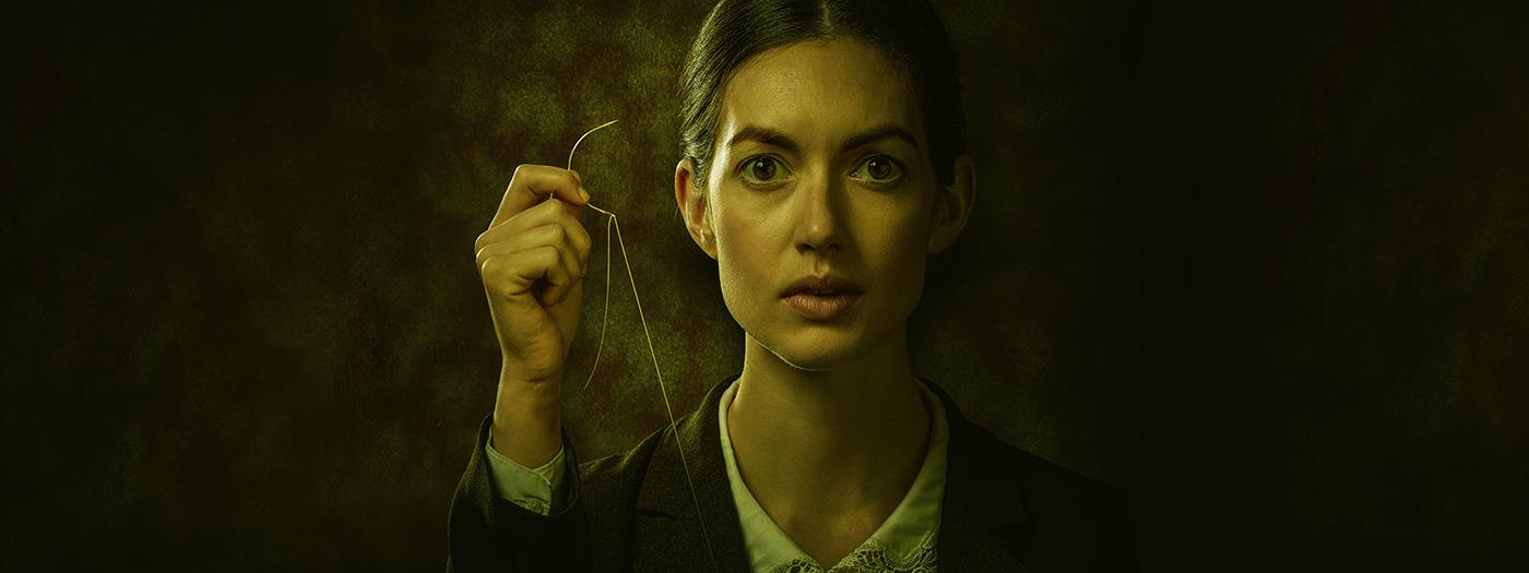 A woman holds a needle and string in her hand