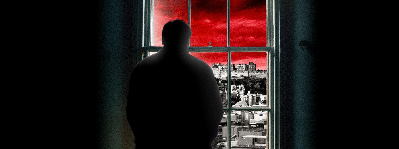 A man in shadows looks out of a window, the sky is red