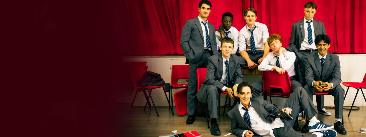 School boys sat on red chairs in school uniform